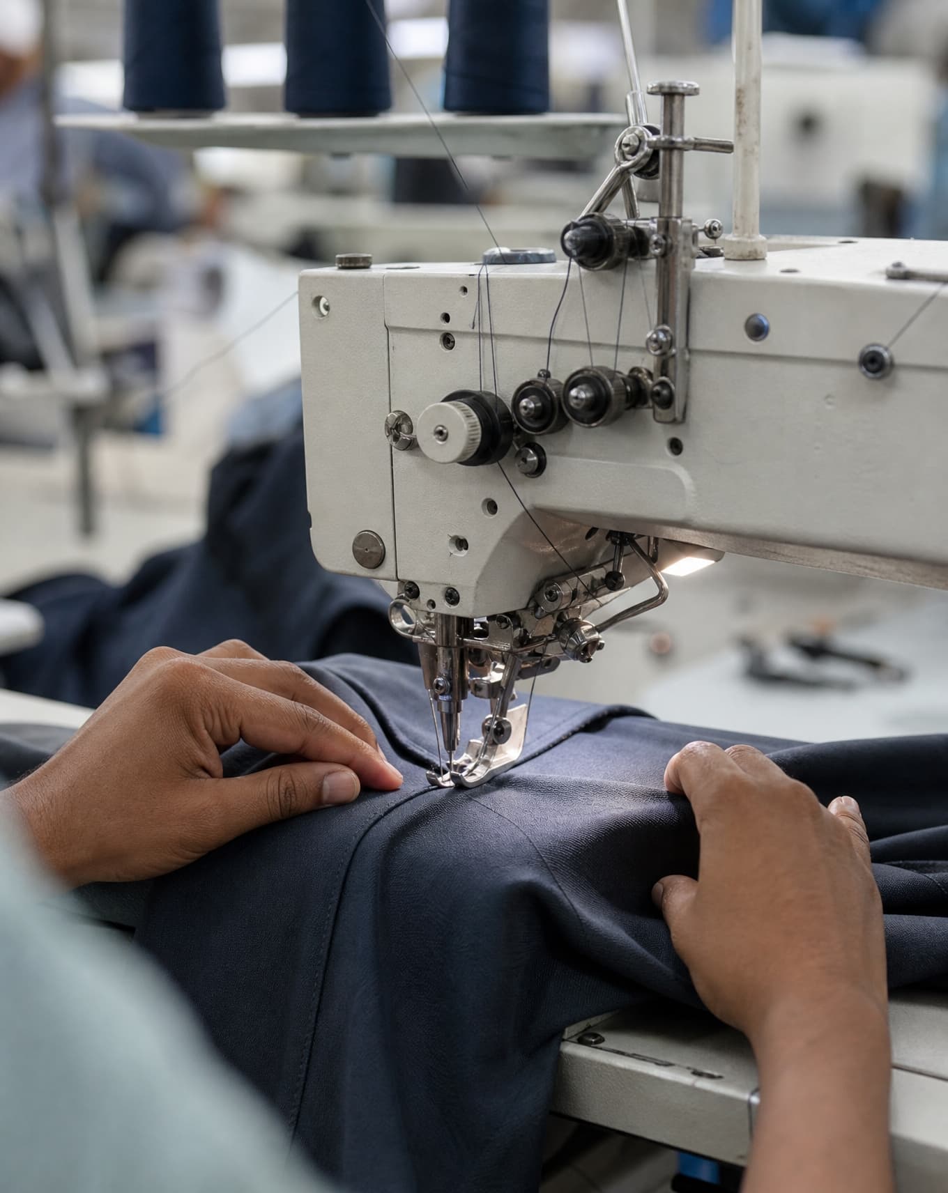 An operator's hands guiding fabric through a sewing machine